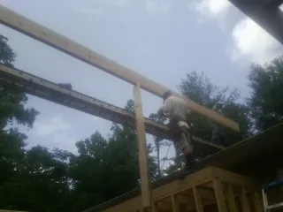 Carpenter setting a ridge beam over a new addition frame — Ice Dam Removal by Roofing Brothers in Klemme