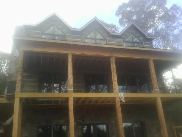 Dormers and porch framing on a large log home under construction — Roof Coating work by our crew in Klemme