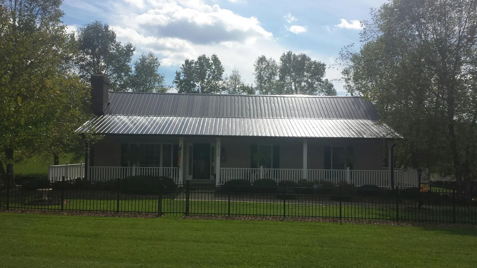 Gray metal roof on a brick ranch with a full width front porch — Gutter Guard Installation work by our crew in Klemme