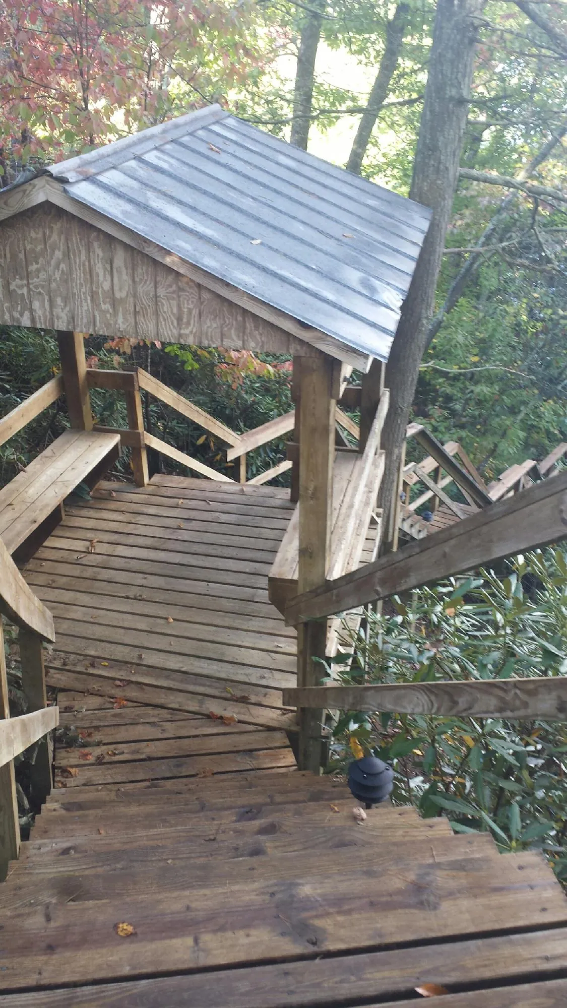 Metal roofed shelter over wooden steps on a wooded walkway — Skylight Repair & Installation work by our crew in Klemme