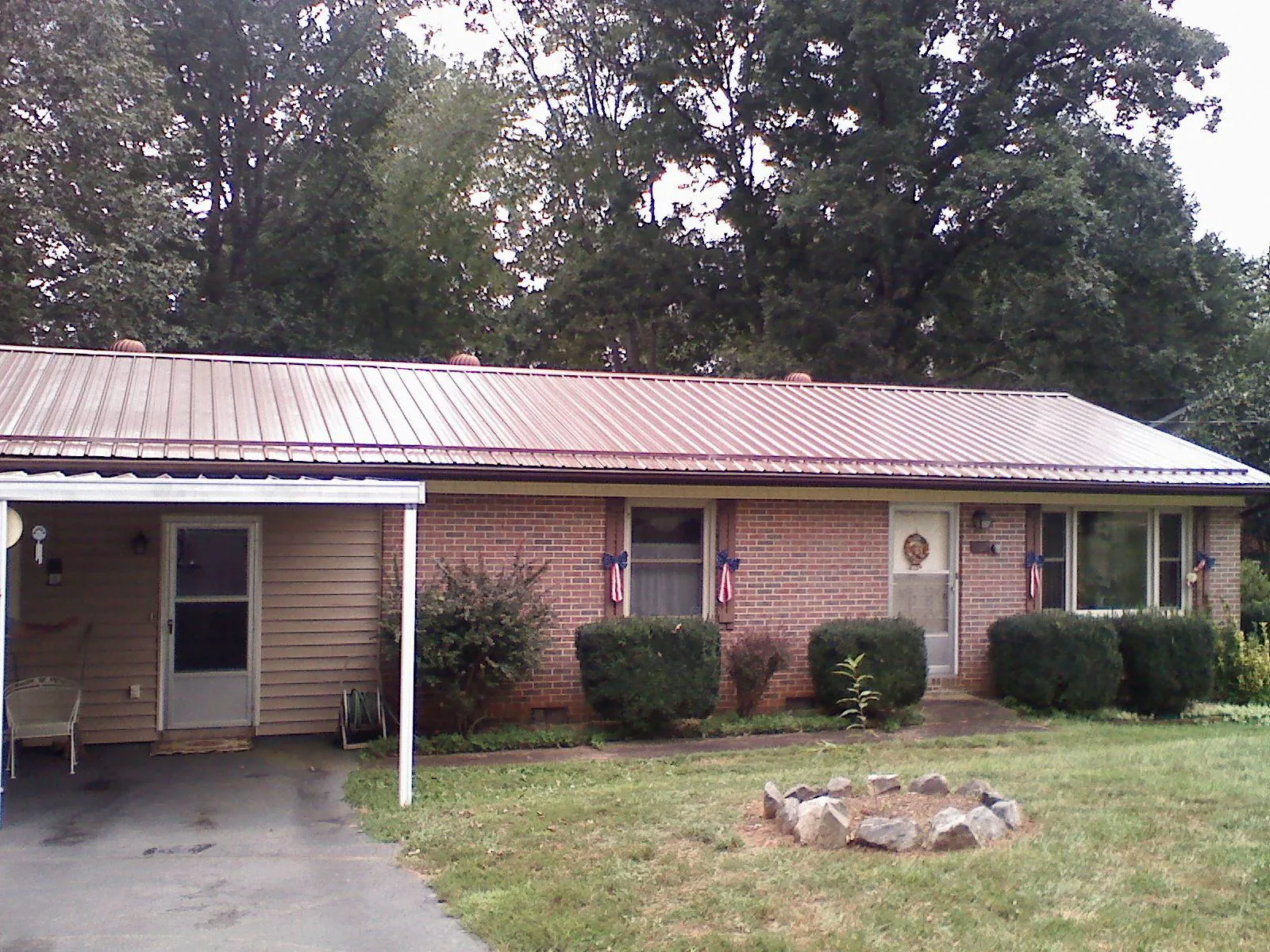 Bronze metal roof and carport on a brick ranch home — Roof Repair work by our crew in Klemme